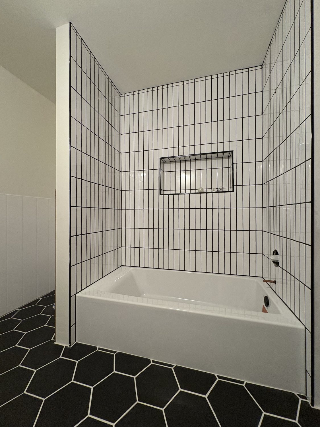 Tiled bathtub surround with contrasting dark floor tile